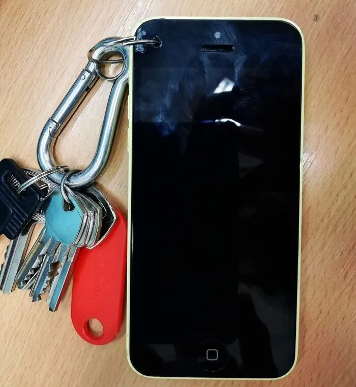 A smartphone with a hole drilled in the corner attached to a keychain for DIY projects
