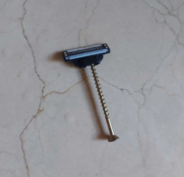 Razor blade head attached to a screw as a makeshift razor handle, an unusual DIY project.
