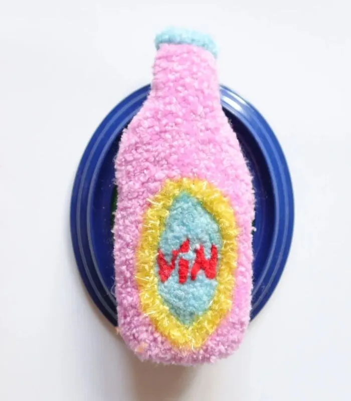 Tufted pink wine bottle artwork on a blue base by Ina Dyreborg