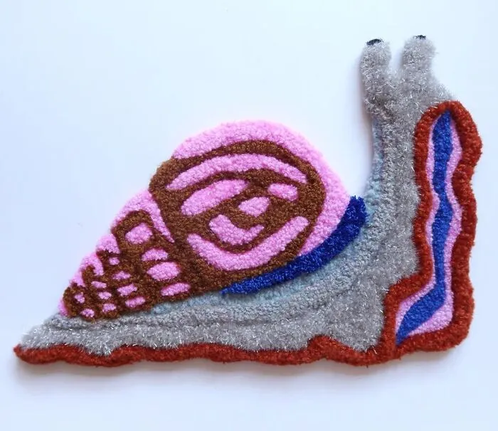 A colorful tufted textile art of a snail by Ina Dyreborg