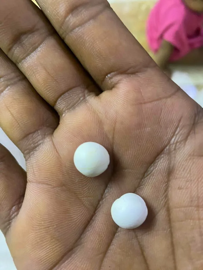 Hand holding small white round objects resembling pearls, related to creepy mysteries around the web.