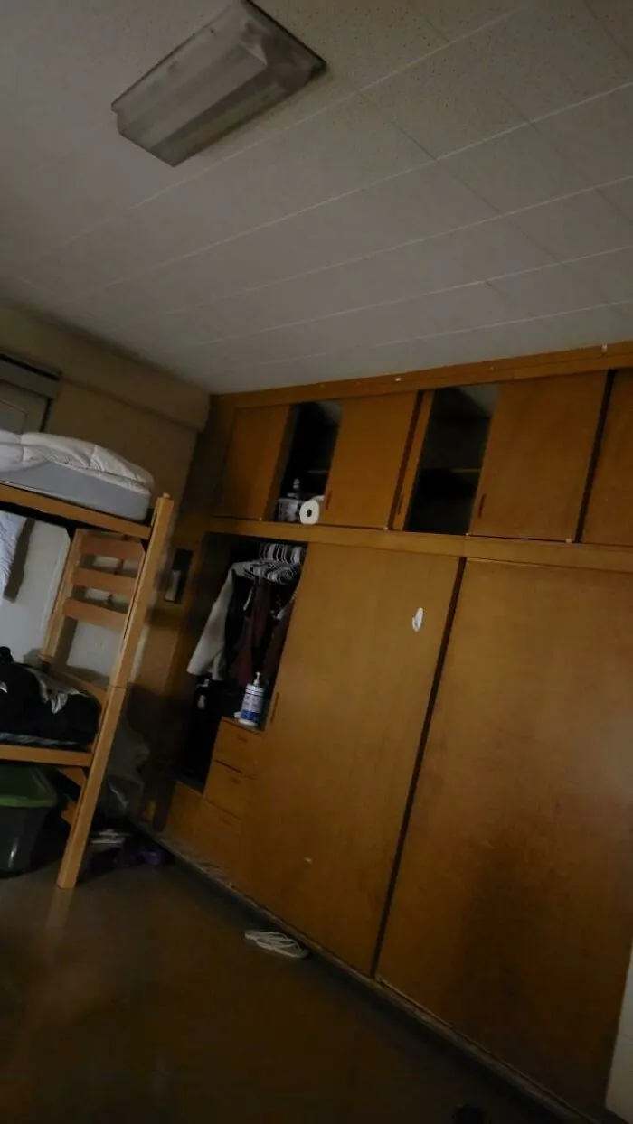 A messy college dorm room with bunk beds and wooden closets from crazy roommate stories