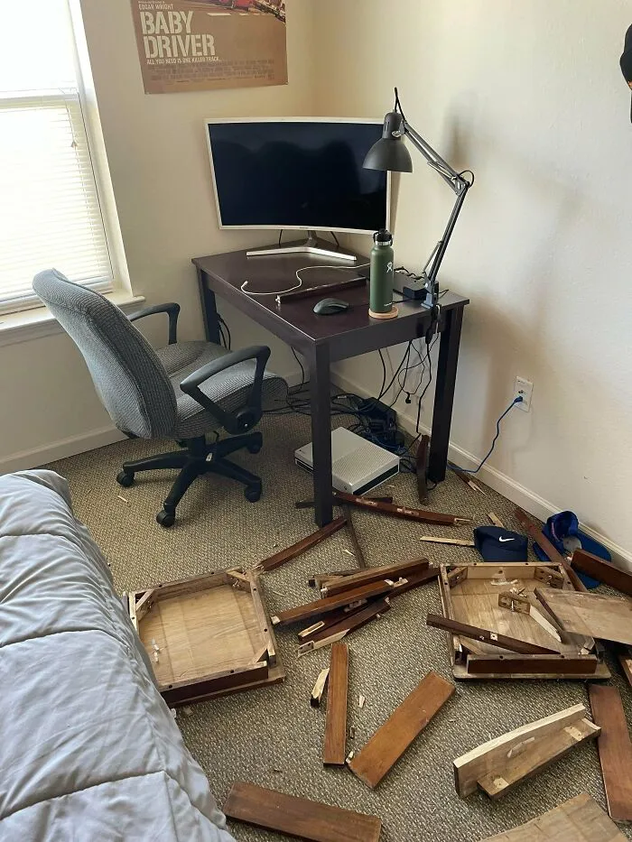 Broken wooden furniture on the bedroom floor next to a study desk, illustrating funny roommate stories.