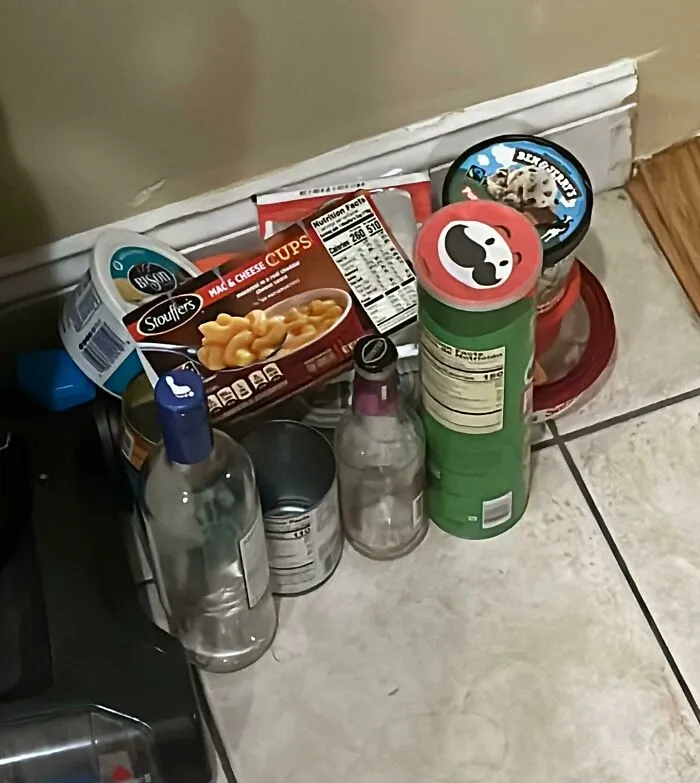 Empty food packaging and bottles on the floor as told in roommate stories about messy living