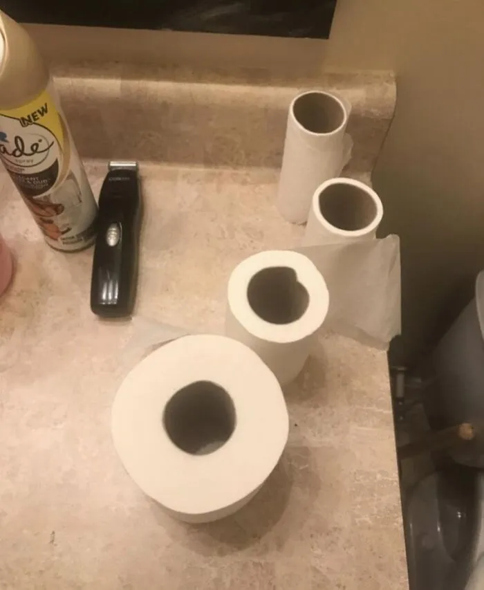 Several mostly empty toilet paper rolls left on a bathroom counter, typical roommate behavior