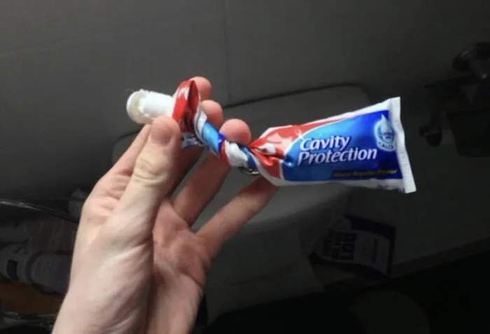 Hand holding a twisted toothpaste tube, illustrating annoying roommate stories of bad bathroom habits