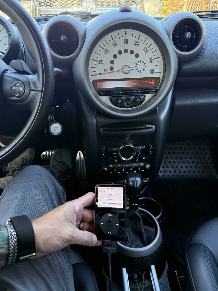 An old iPod classic playing music connected inside a car, perfect for vintage tech finds