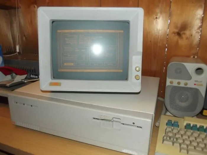 A chunky vintage tech computer monitor with a green screen display and keyboard on a desk