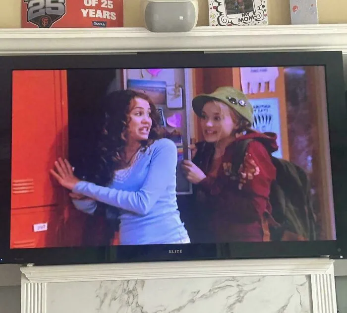 A wide flat-screen TV displaying a scene from Hannah Montana representing vintage tech