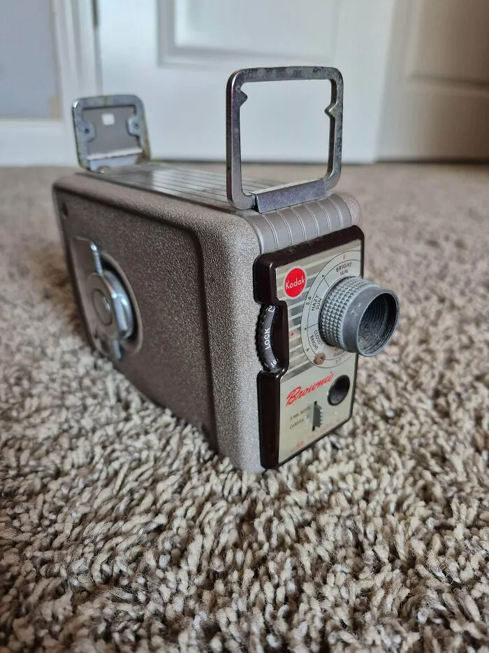 A vintage tech Kodak Brownie movie camera sitting on a carpet