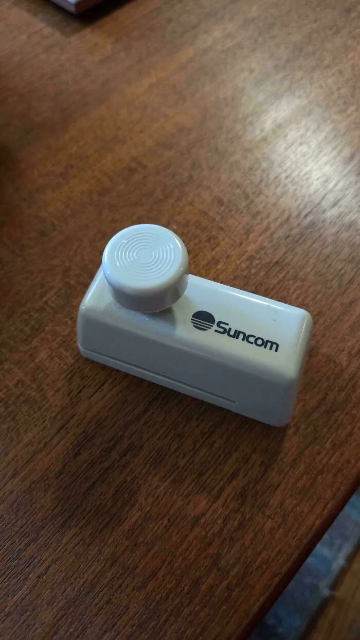 An old Suncom controller adapter on a wooden table, representing vintage tech.