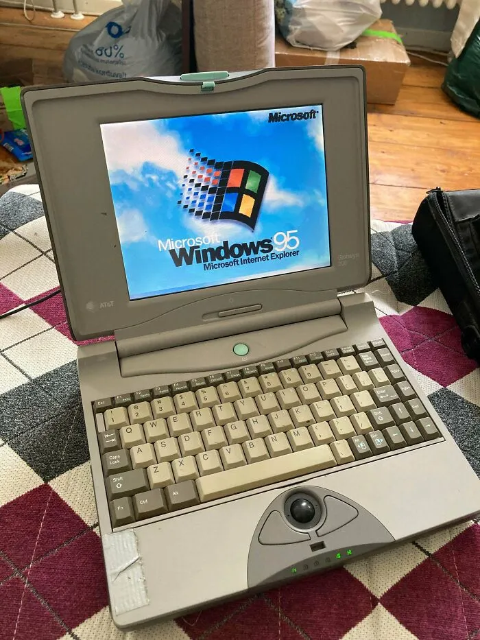 A vintage tech laptop booted up with the classic Microsoft Windows 95 operating system on its screen