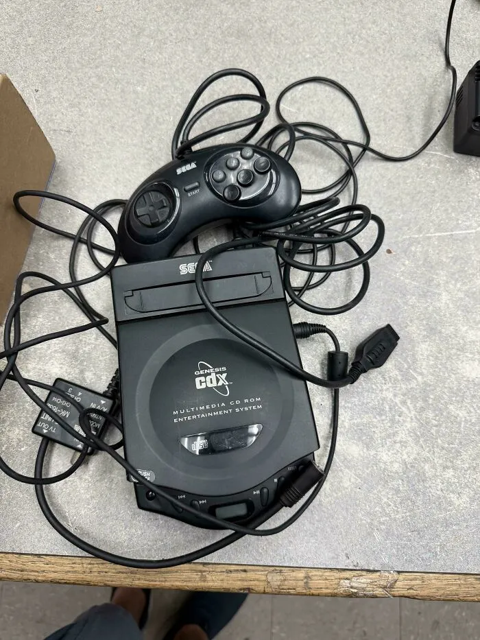 A Sega CDX multimedia console with controller representing vintage tech finds