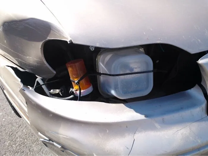 Redneck fixes displaying plastic Tupperware containers used to replace broken headlights on a car.