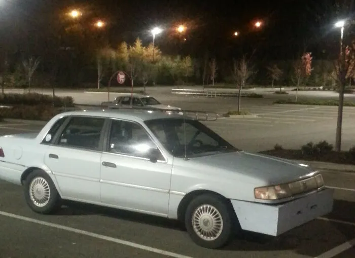 Sedan parked at night with a custom DIY front bumper, illustrating unique redneck fixes.