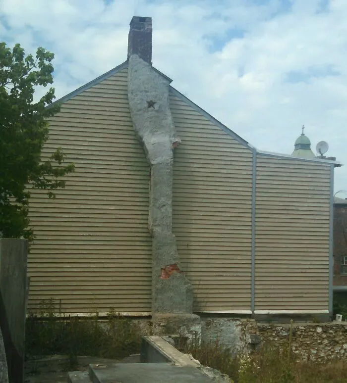 Crude concrete plaster repair on a house chimney showing redneck fixes