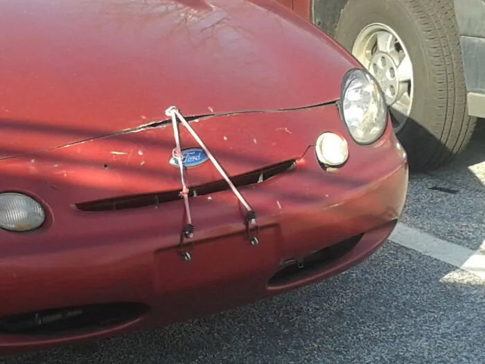 Bungee cords holding down a car hood as a funny redneck fix