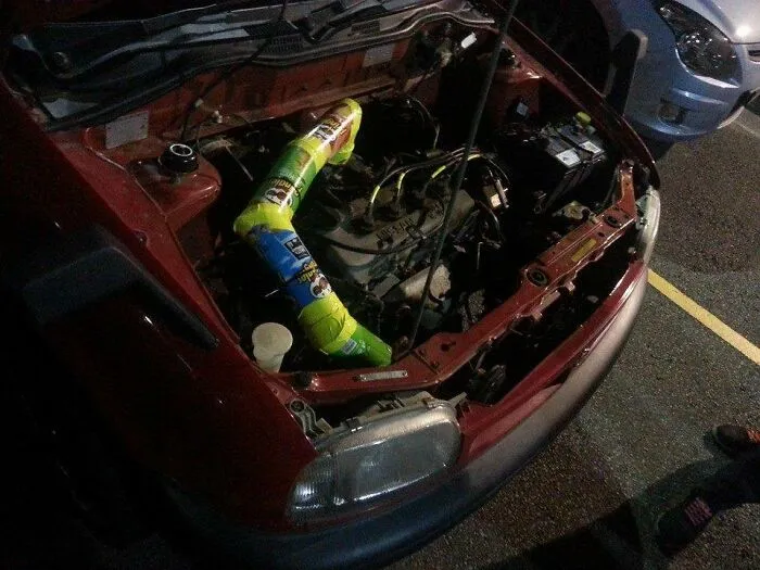 A car engine intake pipe improvised using Pringles cans as a hilarious redneck fix.