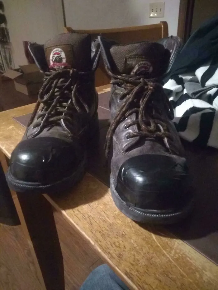 Work boots with black tape repaired toes displaying practical redneck fixes.
