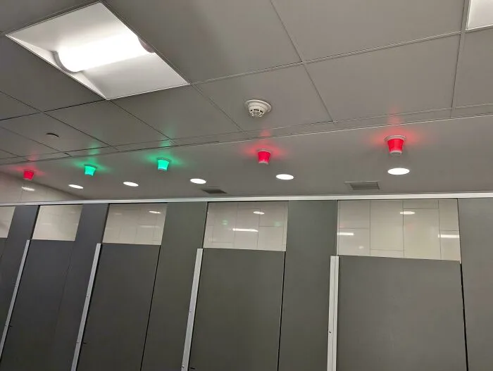 Clever ideas with green and red lights showing vacant and occupied restroom stalls on a ceiling