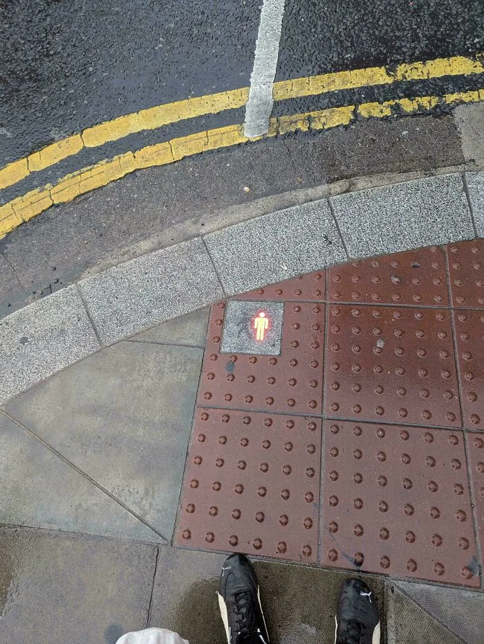 A red pedestrian crossing light integrated into pavement tile, representing clever ideas from people.