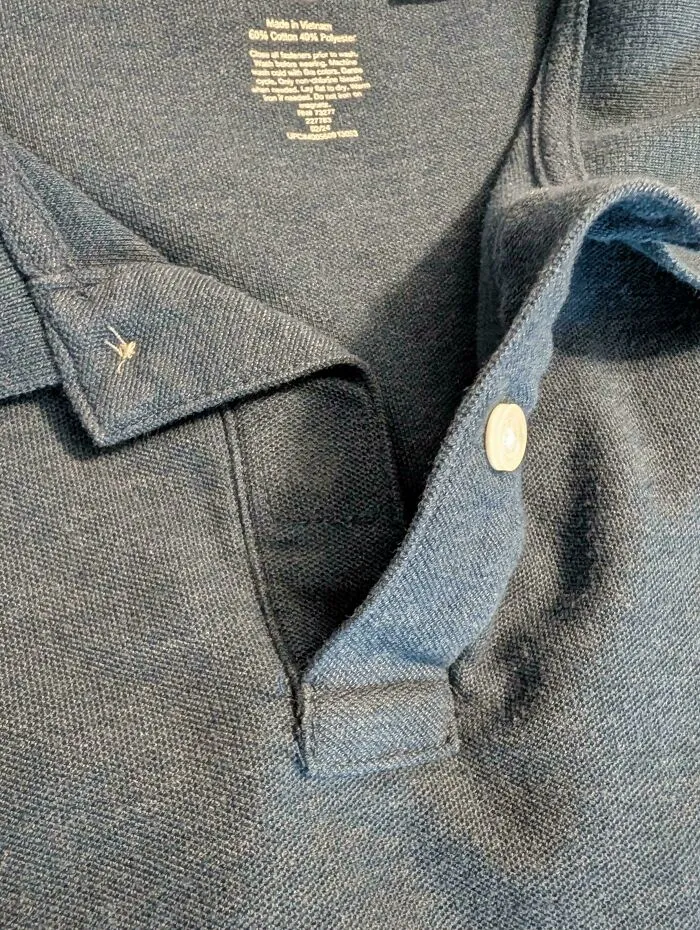 A blue polo shirt featuring a buttonhole but no button, illustrating interesting factory errors