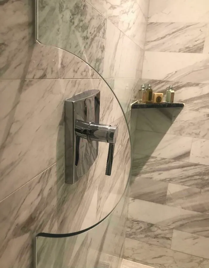 A modern bathroom with a curved glass shower screen featuring clever ideas to accommodate the faucet handle