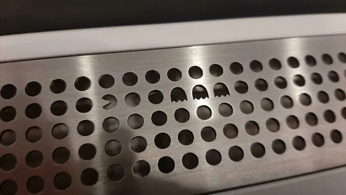 Metal grate with playful Pac-Man and ghost cutouts, illustrating satisfying design ideas.