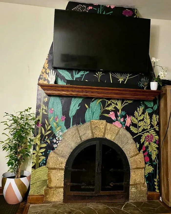 TV mounted above a floral wallpapered fireplace surround in a living room interior design.