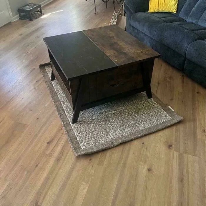 Dark wooden coffee table placed on a small area rug as an interior design choice.