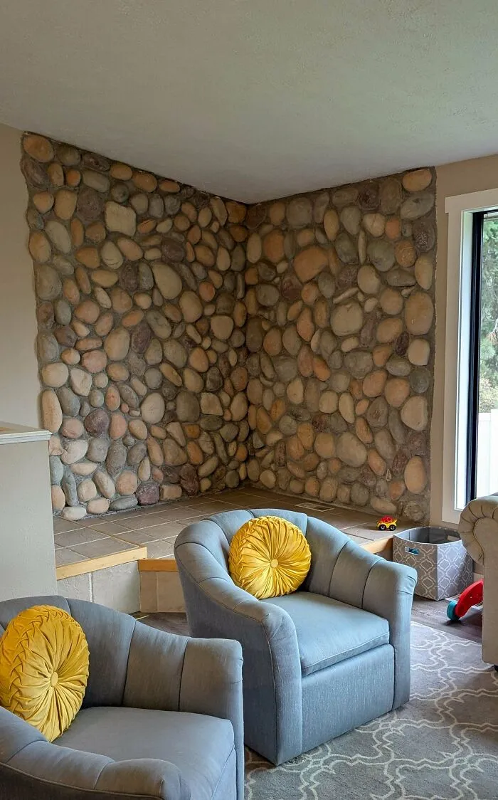Living room corner with a river rock wall feature, a questionable interior design choice.