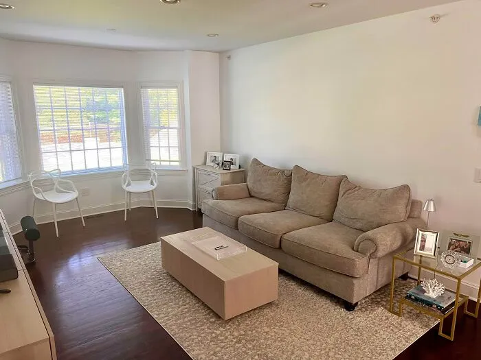Questionable interior design decisions featuring a blank living room wall and beige sofa.