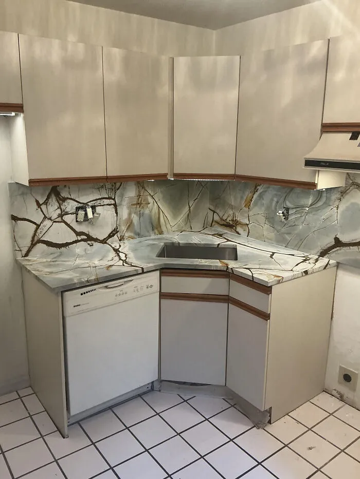 Flawed interior design decisions displaying overly busy marble countertops in a small kitchen.