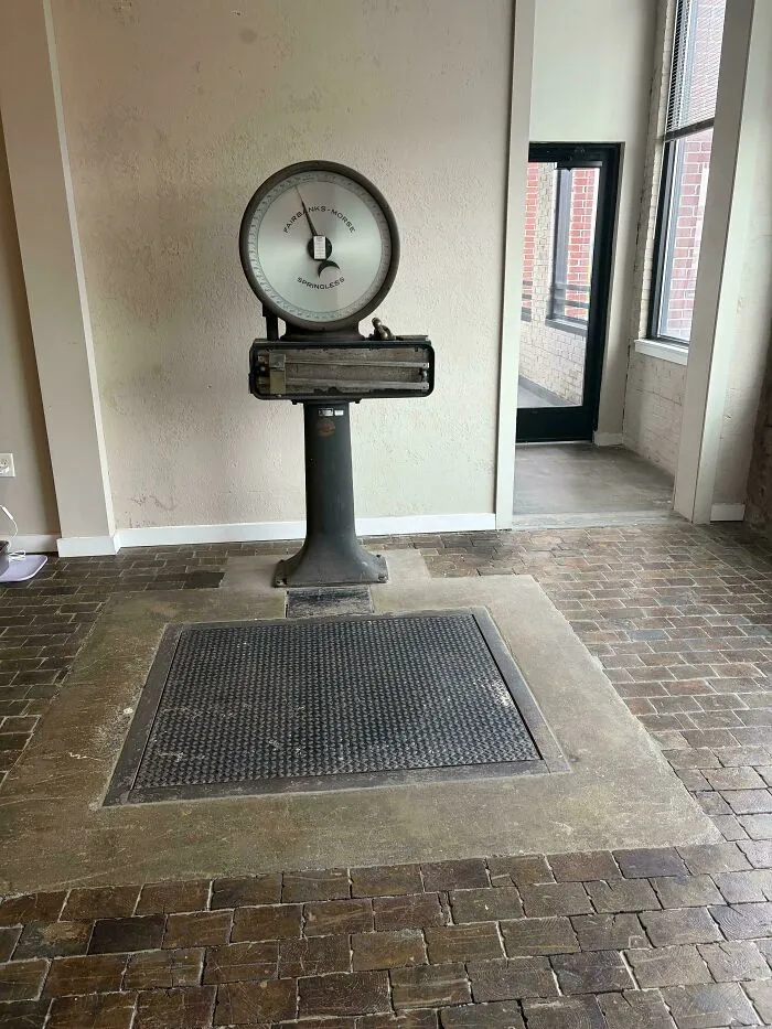 Large vintage mechanical industrial scale built into a brick floor indoor space.
