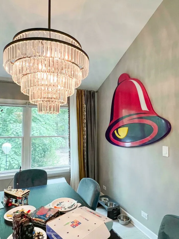Dining room with an ornate crystal chandelier paired with a large Taco Bell logo sign on the wall.