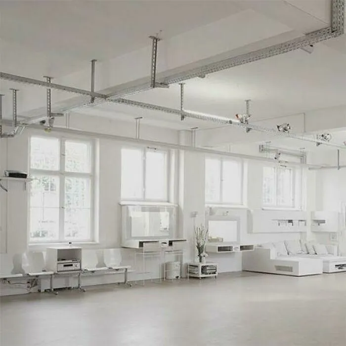 All-white room featuring clinical white furniture and exposed ceiling metal tracks in an extreme interior design style.