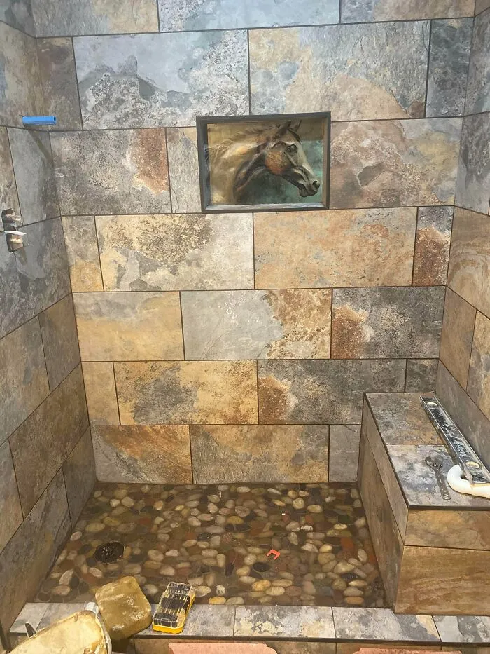 Custom slate tiled shower stall with a horse portrait framed on the wall, showing unique interior design choices.