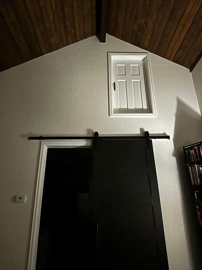 A high white door placed above a sliding barn door, an awkward interior design decision.