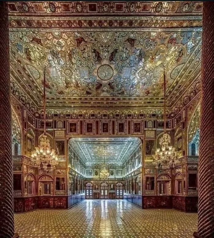 Ornate interior design with intricate mirrored ceiling, gilded walls, and chandeliers in an opulent hall