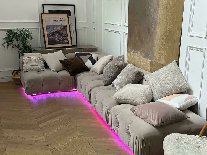Unusual interior design featuring a large sectioned sofa with bright pink LED lighting along the base