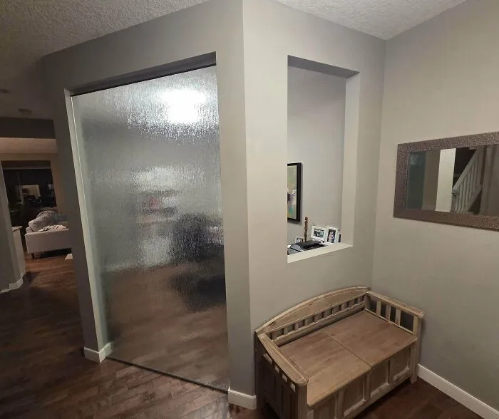 Awkward interior design showing a frosted glass partition and wall cutout in a home hallway