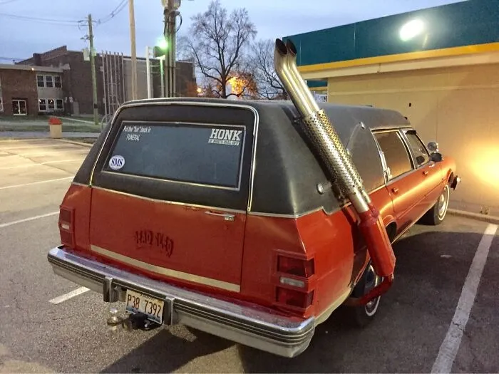 Red hearse with a custom side exhaust pipe showing creative redneck fixes.