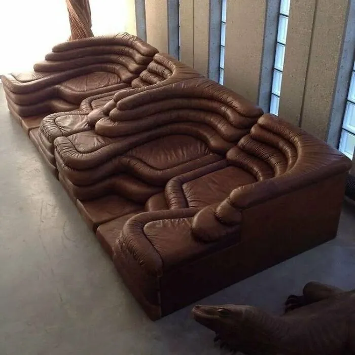 Bizarre interior design giant brown leather couch with layered wavy cushions.