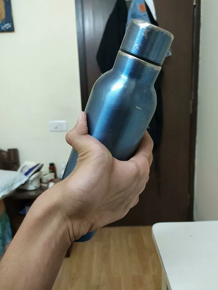 A hand holding a blue metal water bottle, illustrating flexible human anatomy.