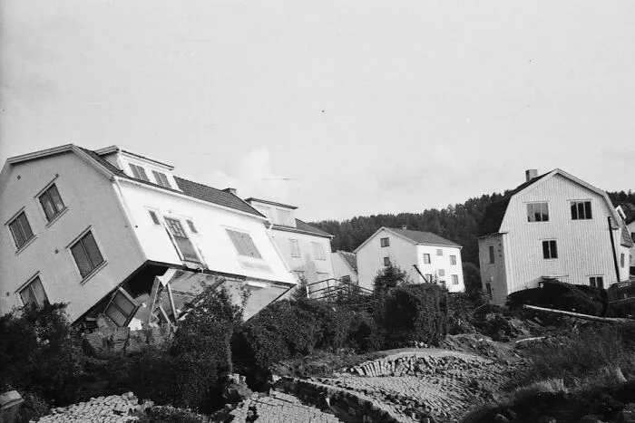 Houses tilted and sliding down a hill after a landslide, depicting expensive accidents.