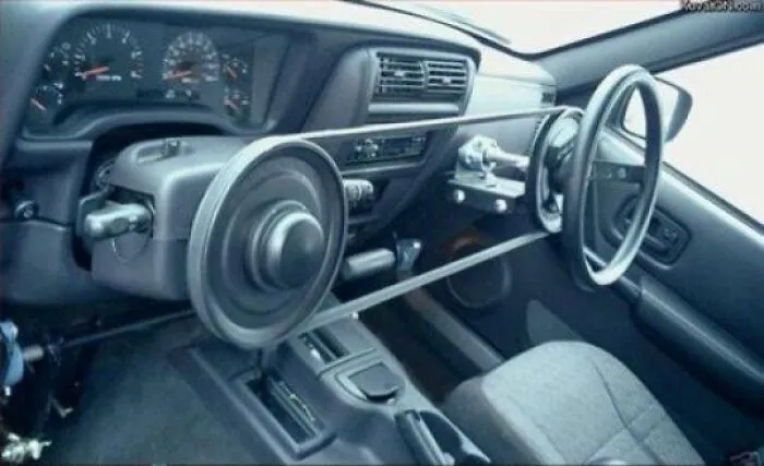 A car interior customized with a belt-driven steering mechanism, an example of unusual redneck fixes.