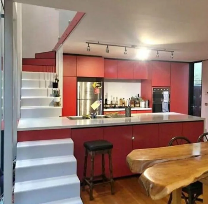 Confusing interior design decision where white stairs block directly into a red kitchen island