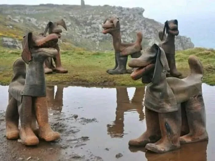Odd and interesting photos of dog statues crafted from old rubber boots standing in a field.