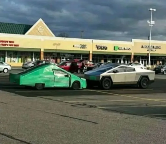 An odd green homemade car parked opposite a Tesla Cybertruck in a retail parking lot.