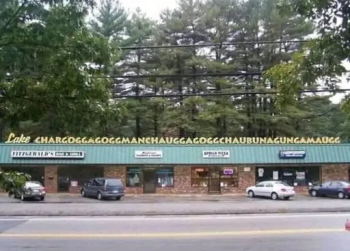 Odd photo of a sign displaying an extremely long single-word lake name above a strip mall.
